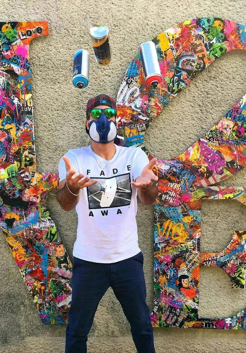 Person in colorful mask and white shirt before butterfly wall art in Aiiroh collection.