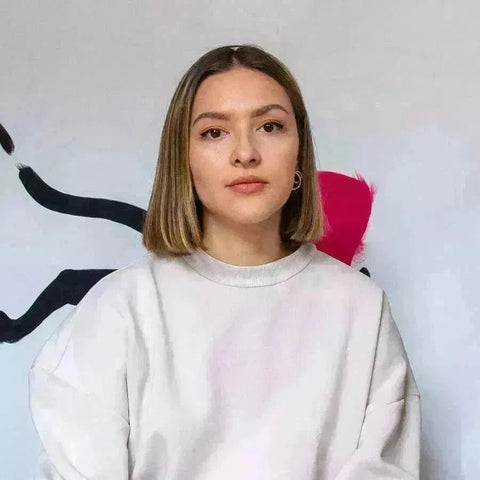 Young woman with blonde hair in a white sweatshirt from Mariah Birsak collection.