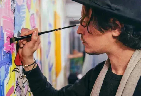 Artist creating vibrant art on canvas using a brush in their mouth in Onizbar collection.