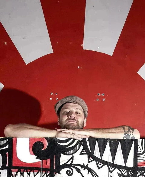 Man in cap peering over patterned barrier against red and white stripes, Paul Vinoy collection.