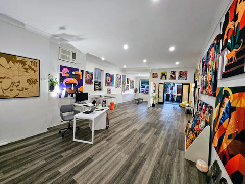 Art gallery displaying various colorful paintings and artworks on white walls.