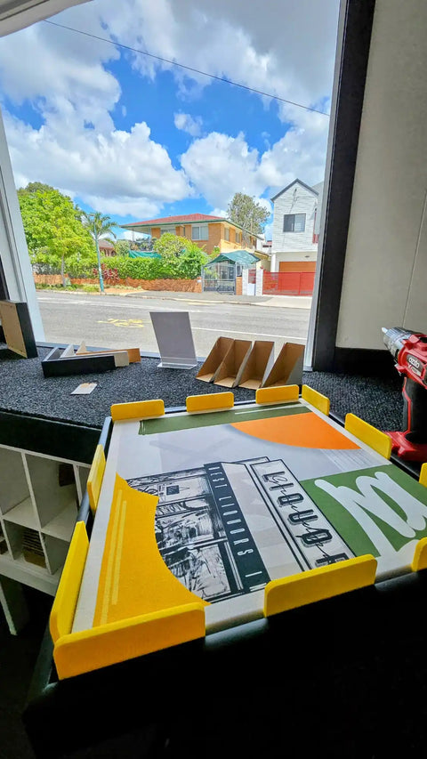 Board game with colorful pieces and a money tray visible on a windowsill.