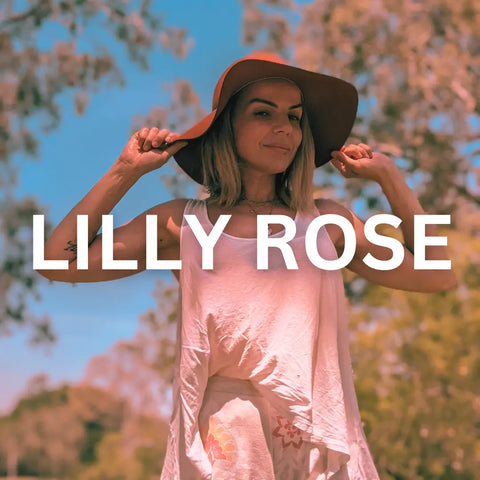 Woman wearing a wide-brimmed hat and light pink top against a backdrop of blossoming trees.