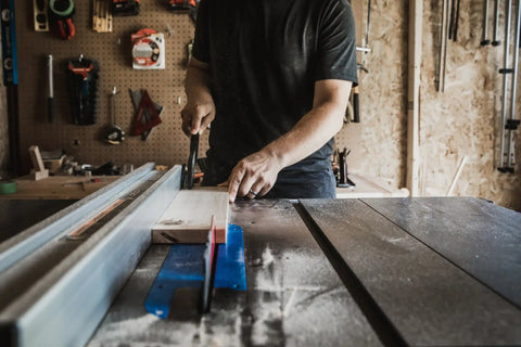 Table saw being operated by a person in a workshop setting.